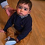toddler, child, indoor, floor, wooden_floor, clothing, sweater, pants, shoes, hand, bracelets, person, portrait, young_child, casual, cute, baby, sitting, looking_at_camera, expression