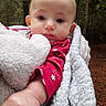 baby, blanket, cheek, child, close_up, clothing, cozy, cute, eyes, face, forest, ground, hand, infant, outdoors, portrait, red_sleeve, soft_texture, trees, wrapped