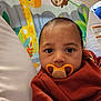 baby, pacifier, infant, face, child, clothing, cute, indoor, portrait, close_up, resting, animal_print, colorful, seat, hand, young_child, cozy, expression, baby_girl, baby_boy