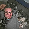 Robby participe au concours pour gagner de l'argent avec cette photo : man, dog, sleeping, couch, blanket, glasses, plaid_shirt, indoor, relaxing, pet, cozy, rest, napping, companion, furniture, casual_clothing, paw, head, comfort, home