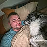 man, dog, sleeping, bed, blanket, pillow, indoor, rest, cozy, friendship, relaxation, comfort, casual_clothing, animal, pet, domestic_life, face, fur, spot, cuddle