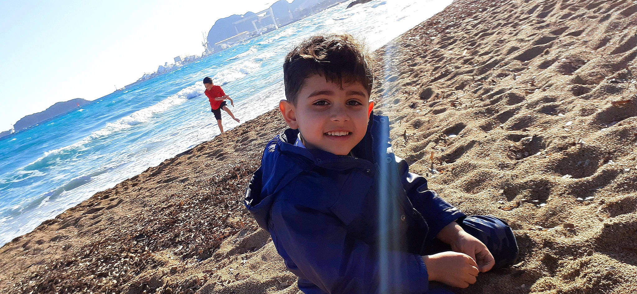 Emile participe au concours pour gagner de l'argent avec cette photo : azure, beach, body_of_water, fun, happy, horizon, human, joy, landscape, leisure, natural_environment, people, people_in_nature, people_on_beach, person, recreation, sand, sky, smile, toddler