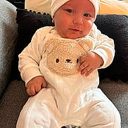 Aymen participe au concours pour gagner de l'argent avec cette photo : baby, infant, child, white_outfit, hat, teddy_bear, couch, pillow, smile, cute, indoor, cozy, soft_toys, plush, clothing, person, portrait, sitting, cute_expression, home