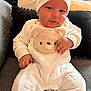 baby, infant, child, white_outfit, hat, teddy_bear, couch, pillow, smile, cute, indoor, cozy, soft_toys, plush, clothing, person, portrait, sitting, cute_expression, home
