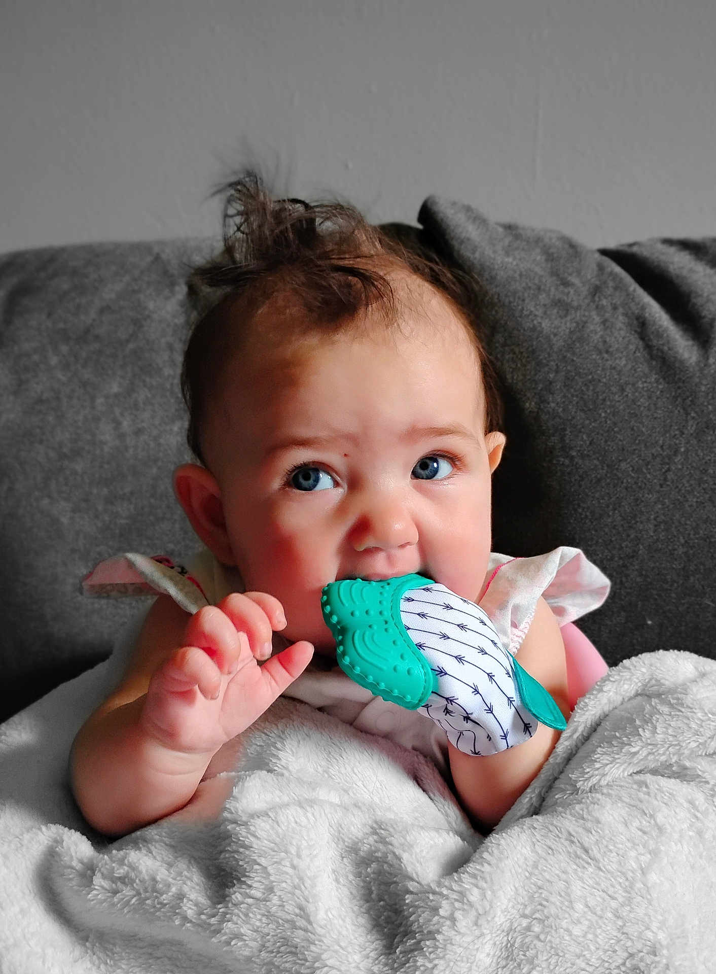 Maisie Jo is registered to the contest to win money with this photo: baby, infant, teething, mitten, blanket, blue_eyes, curly_hair, couch, indoor, cute, child, person, soft_texture, closeup, comfort, young, hand, expression, adorable, warm