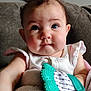 baby, child, blue_eyes, teething_toy, blanket, couch, curly_hair, infant, close_up, cute, person, indoors, soft_lighting, white_clothing, plush, portrait, sitting, chubby_cheeks, face, expression