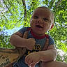 baby, infant, child, onesie, tattoos, arms, outdoor, trees, greenery, sky, daylight, smiling, happy, person, nature, portrait, holding, playful, cute, young