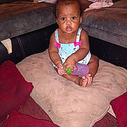 Kenslee joined the competition — help win amazing prizes! baby, child, bottle, cushion, sofa, living_room, indoor, person, clothing, footwear, hair, curly_hair, sitting, pink_bow, blue_outfit, carpet, pillow, expression, cute, young