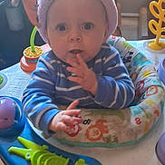 Parker Lee joined the competition — help win amazing prizes! baby, infant, hat, striped_clothing, blue_clothing, activity_center, toy, indoor, child, face, hand, expression, curious, seat, play, colorful, home, furniture, person, young