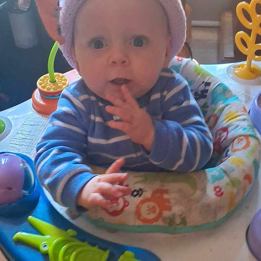 Parker Lee joined the competition — help win amazing prizes! baby, infant, hat, striped_clothing, blue_clothing, activity_center, toy, indoor, child, face, hand, expression, curious, seat, play, colorful, home, furniture, person, young