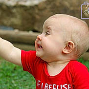 Roger is registered to the contest to win money with this photo: baby, child, smiling, red_shirt, outdoor, toy, grass, happy, portrait, cute, infant, playful, young_child, face, head, hand, greenery, nature, expression, photography