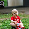 Roger is registered to the contest to win money with this photo: baby, child, grass, outdoor, toy, fire_truck, red_shirt, shorts, barefoot, sitting, curious, greenery, nature, playing, young_child, portrait, daylight, cute, infant, photography