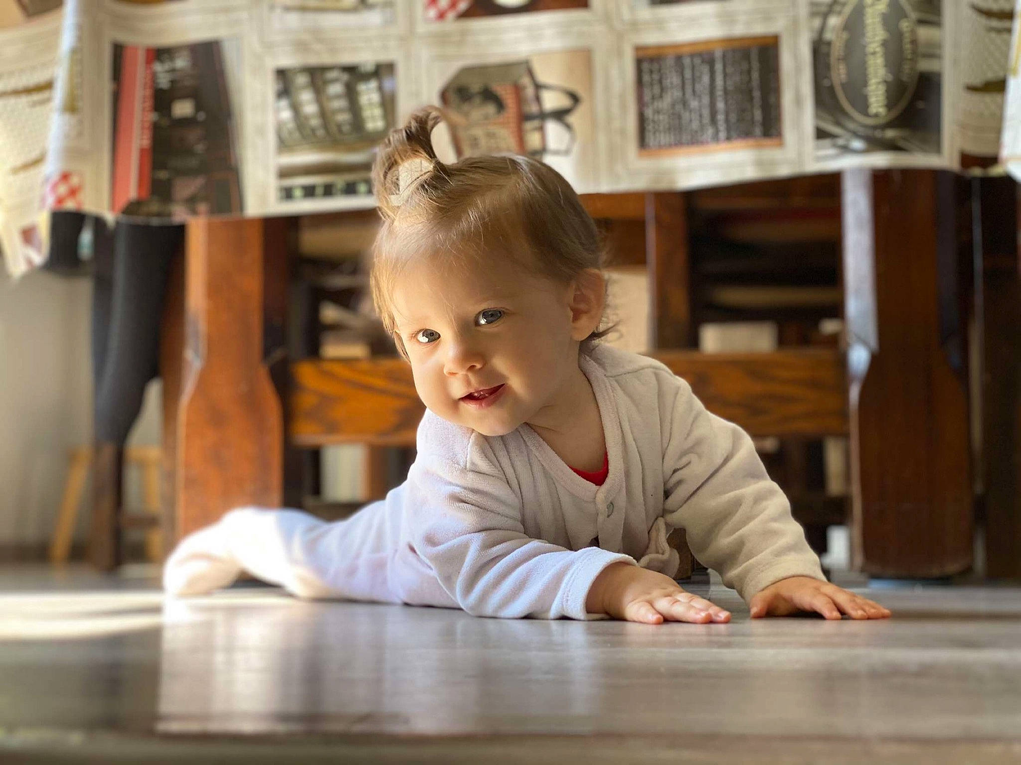 Hilona participe au concours pour gagner de l'argent avec cette photo : baby, baby_toddler_clothing, bookcase, child, crawling, floor, flooring, fun, happy, hardwood, leisure, person, picture_frame, room, shelf, sitting, smile, t_shirt, toddler, wood