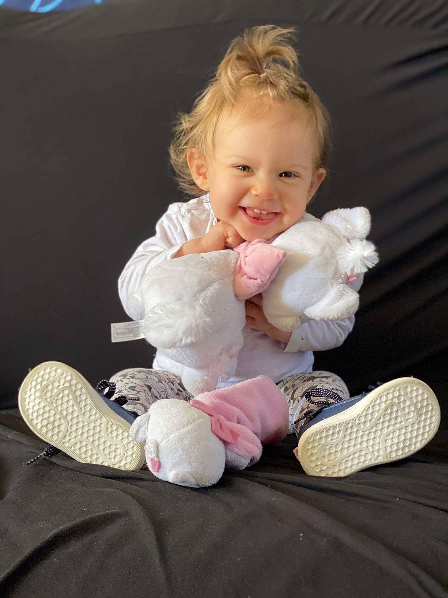 Hilona participe au concours pour gagner de l'argent avec cette photo : baby, baby_toddler_clothing, cheek, comfort, face, finger, foot, hair, happy, human_body, joy, knee, leg, person, pink, skin, sleeve, smile, sneakers, sock