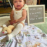 Nomi is registered to the contest to win money with this photo: animal, baby, bird, clothing, crying, cushion, face, furniture, head, homedecor, hosiery, indoors, person, photography, plush, portrait, quilt, sad, sitting, sock