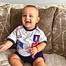baby, child, smiling, sitting, couch, pillow, indoor, clothing, shorts, tshirt, football, world_cup, france, happy, cute, portrait, skin, hand, foot, home