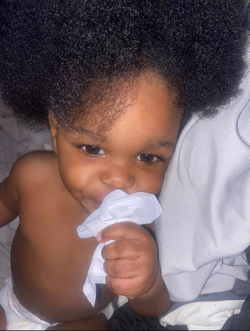 Marcus is registered to the contest to win money with this photo: toddler, child, afro_hair, baby, diaper, hand, face, eyes, skin, bedding, cloth, soft, cute, closeup, indoor, portrait, expression, playful, curious, infant