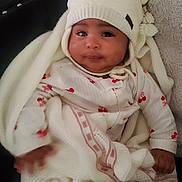 Emily is registered to the contest to win money with this photo: baby, blanket, blanket_texture, cherry_pattern, child, clothing, couch, cozy, cushion, eyes, face, fluffy_throw, hand, indoor, infant, knit_hat, onesie, portrait, smile, swaddle