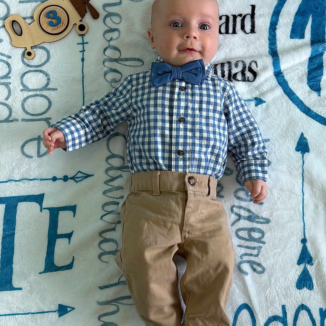 Theodore joined the competition — help win amazing prizes! baby, infant, boy, blue_shirt, bow_tie, khaki_pants, barefoot, toy_airplane, blanket, name_text, personalized_blanket, lying_down, portrait, cute, smiling, child, indoors, clothing, face, young