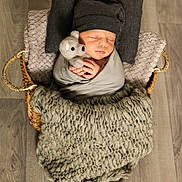 Maël participe au concours pour gagner de l'argent avec cette photo : baby, baby_products, baby_sleeping, baby_toddler_clothing, cap, comfort, doll, fur, grey, headgear, human_body, knit_cap, linens, product, sitting, stuffed_toy, textile, toddler, wood, wool