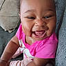 Leoni is registered to the contest to win money with this photo: baby, child, smiling, laughing, pink_shirt, couch, pillow, happy, indoor, person, cute, infant, sitting, face, joyful, skin, expression, young, toddler, hand