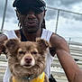 Nala is registered to the contest to win money with this photo: man, dog, pet, outdoor, chain_link_fence, cap, sunglasses, yellow_harness, brown_dog, white_tank_top, casual, portrait, fence, cloudy_sky, closeup, smile, leisure, person, animal, friendship