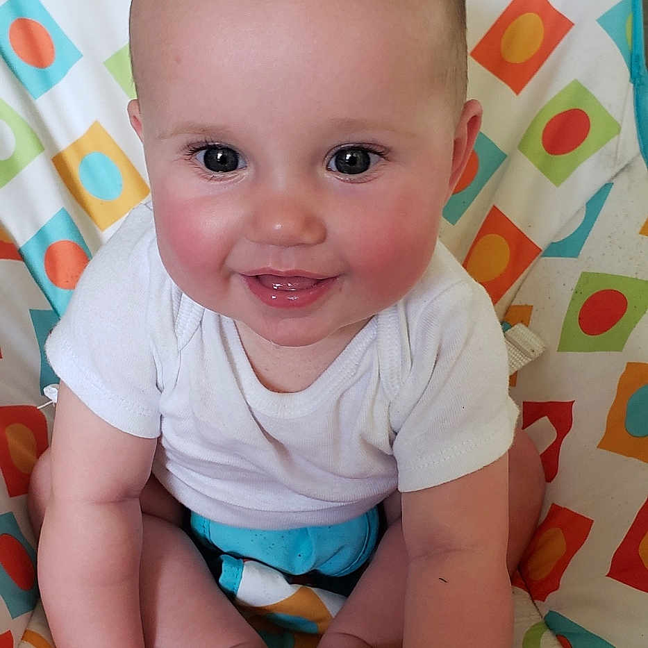 Oakley is registered to the contest to win money with this photo: baby, cheeks, child, closeup, colorful_chair, cute, eyes, feet, hands, happy, head, indoors, infant, mouth, patterned_chair, portrait, sitting, skin, smiling, white_shirt