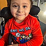 child, toddler, smiling, portrait, wheelchair, seated, red_shirt, mario, cartoon, indoors, hospital, chair, face, eyes, brown_hair, happy, close_up, clothing, supportive_equipment, photography