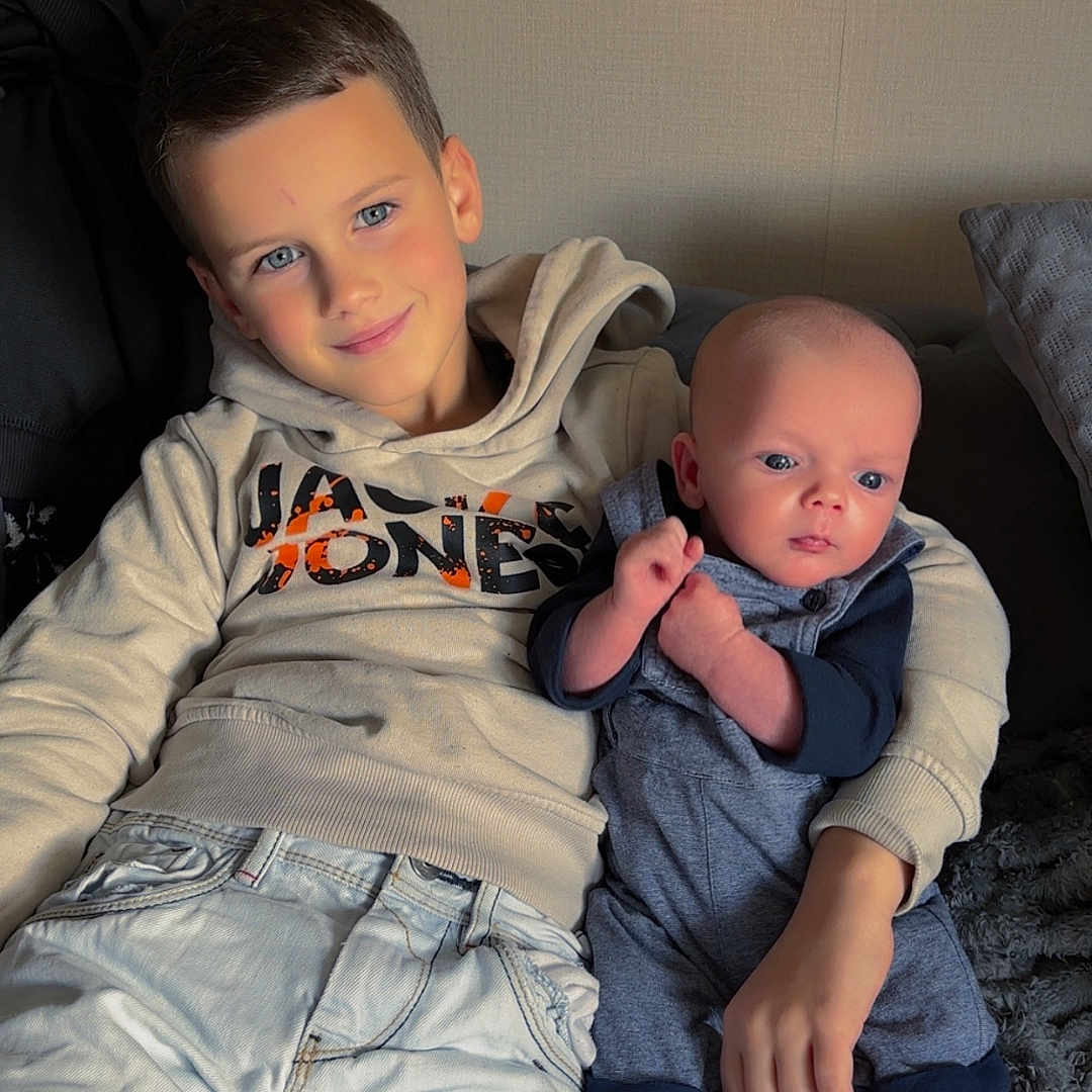 Kimberly Le Moal participe au concours pour gagner de l'argent avec cette photo : baby, blanket, boy, child, clothing, couch, cozy, cute, family, home, hoodie, indoor, jeans, person, portrait, shoes, sitting, smile, socks, toddler