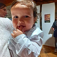 Mathis participe au concours pour gagner de l'argent avec cette photo : toddler, child, person, white_clothing, indoor, portrait, curly_hair, face, hand, woman, lace_dress, background, poster, floor, wooden_beams, smile, fingers, casual, people, light