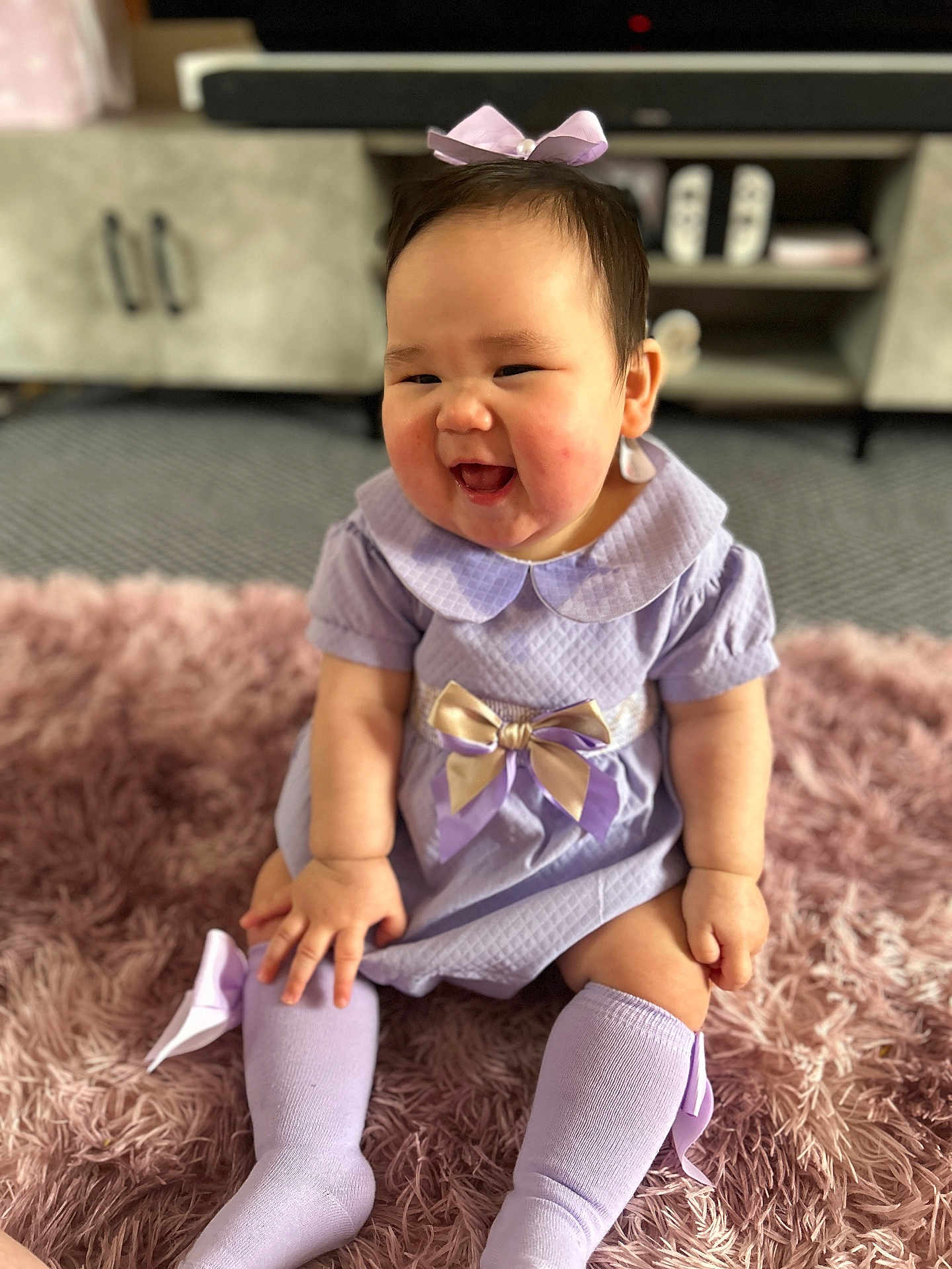 Yurie joined the competition — help win amazing prizes! baby, child, smiling, sitting, lilac_dress, bow, knee_socks, pink_rug, happy, indoors, cute, infant, portrait, childrens_clothing, fun, adorable, furniture, carpet, home, young_child