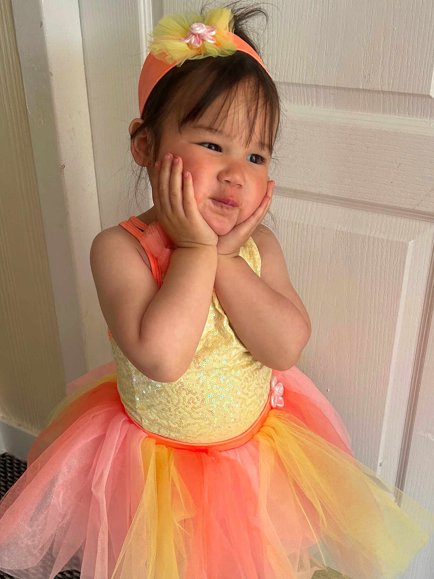 Niomie is registered to the contest to win money with this photo: child, girl, tutu, dress, headband, flower, hands_on_face, indoor, cute, smile, pose, young_child, fashion, playful, portrait, colorful, sequins, happy, person, tulle