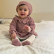 Dahlia Mila joined the competition — help win amazing prizes! baby, child, infant, smiling, knitted_hat, knitted_sweater, pink_clothing, sitting, bed, blanket, happy, cute, portrait, indoors, soft_lighting, warm_colors, cozy, person, toddler, face