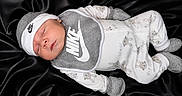 Messiah is registered to the contest to win money with this photo: baby, newborn, sleeping, nike, clothing, hat, mittens, onesie, footed_pajamas, bibs, black_background, soft_texture, cute, infant, portrait, cozy, peaceful, child, apparel, sleep