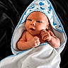 Messiah is registered to the contest to win money with this photo: baby, newborn, towel, hooded_towel, blue_trim, infant, skin, cute, face, hands, black_background, wrapped, small, child, person, laying, curious, soft, fresh, indoors