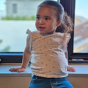 Elianah participe au concours pour gagner de l'argent avec cette photo : casual_clothing, child, curious, daylight, face, floral_print, girl, hair_tied_back, hands, indoor, jeans, natural_light, playful, portrait, sitting, toddler, top, window, windowsill, young_child