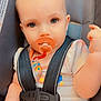 Delilah is registered to the contest to win money with this photo: baby, pacifier, car_seat, child, infant, safety_harness, cute, person, seatbelt, clothing, hand, face, eyes, straps, indoor, closeup, skin, head, expression, child_safety