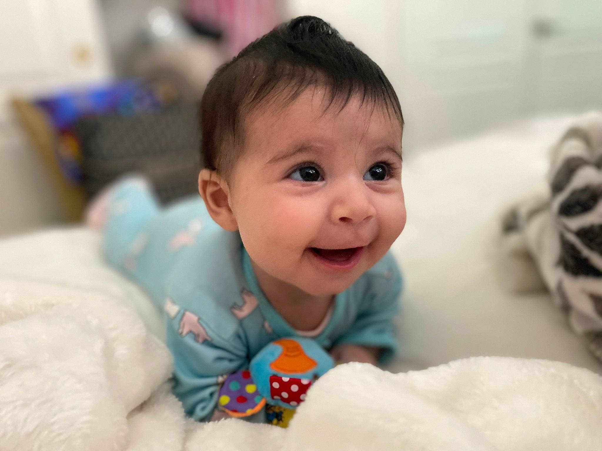 Arya is registered to the contest to win money with this photo: baby, baby_toddler_clothing, cheek, child, comfort, dress, eyebrow, eyelash, fun, happy, human_body, iris, linens, nose, person, room, sitting, skin, sleeve, smile