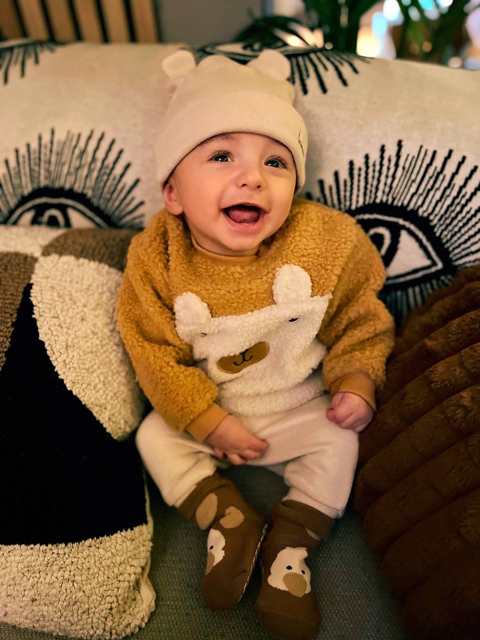 Theo is registered to the contest to win money with this photo: baby, baby_toddler_clothing, cap, chair, child, comfort, couch, fashion_accessory, fur, happy, hat, headgear, headwear, knit_cap, lap, person, sitting, skin, sleeve, smile