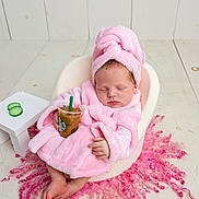 Ainsley Kay is registered to the contest to win money with this photo: baby, sleeping, pink_robe, turban, iced_coffee, cup, chair, cucumber_slices, table, pink_rug, curly_rug, infant, cozy, relaxed, indoor, wooden_floor, cute, small_hands, foot, portrait