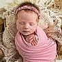 newborn, baby, sleeping, pink_blanket, headband, crochet_lace, wrapped, peaceful, close_up, portrait, infant, soft_texture, delicate, cute, resting, hands_together, toes, cozy, indoors, warm_colors