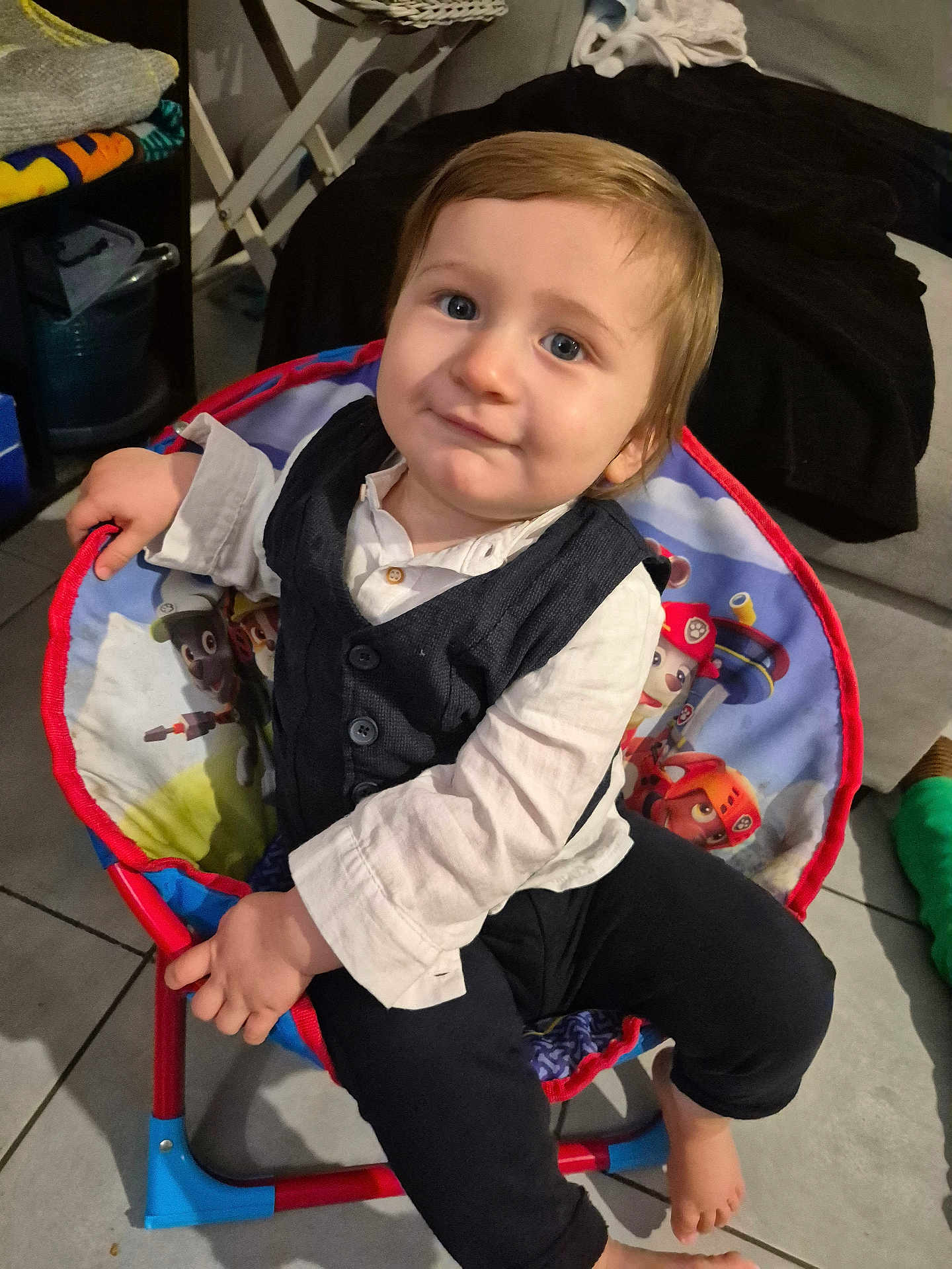 Alessio participe au concours pour gagner de l'argent avec cette photo : toddler, child, boy, chair, indoor, smile, face, clothing, vest, shirt, barefoot, floor, cartoon, toy, hand, blue_eyes, hair, furniture, cute, portrait