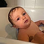 baby, bathtub, bath, water, wet_hair, child, skin, face, head, eyes, curious, indoors, tile_wall, arm, hand, young_child, portrait, person, bathroom, sitting