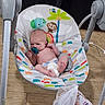 baby, infant, child, bouncer, pacifier, sitting, lying_down, face, feet, toys, elephant, monkey, colorful, indoor, wooden_floor, baby_gear, chair, blanket, home, portrait