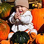 baby, child, pumpkin, orange, green_pumpkin, beanie, clothing, outdoor, autumn, fall, smile, hands, sitting, cute, seasonal, harvest, nature, sunlight, festive, happy