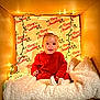 Azari is registered to the contest to win money with this photo: baby, child, red_sweater, bow, christmas_lights, cardboard_box, blanket, festive, holiday, smiling, face, indoors, cozy, wrapped, decoration, cute, portrait, happy, seasonal, wrapped_gift
