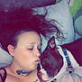 woman, dog, sleeping, couch, pillow, tattoo, necklace, black_clothing, indoor, closeup, pet, affection, snuggling, relaxing, face, hair, collar, toy, resting, companion