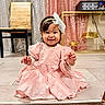 Amira Sophia joined the competition — help win amazing prizes! child, baby, smiling, pink_dress, headband, indoor, floor, curtains, wooden_chair, table, happy, portrait, sitting, cute, toddler, girl, clothing, face, person, decor