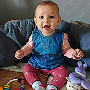 Haïcéa a rejoint le concours — aidez-le/la à gagner de superbes lots ! baby, child, smiling, denim_dress, pink_leggings, socks, toys, plush_toy, teething_ring, colorful, indoor, sitting, happy, person, face, cute, floor, blanket, wooden_ring, playtime