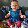 baby, child, smiling, denim_dress, pink_leggings, socks, toys, plush_toy, teething_ring, colorful, indoor, sitting, happy, person, face, cute, floor, blanket, wooden_ring, playtime